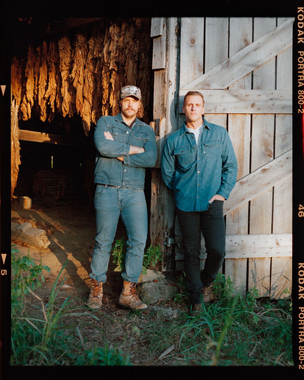 Jared and co-host leaning against tobacco barn
